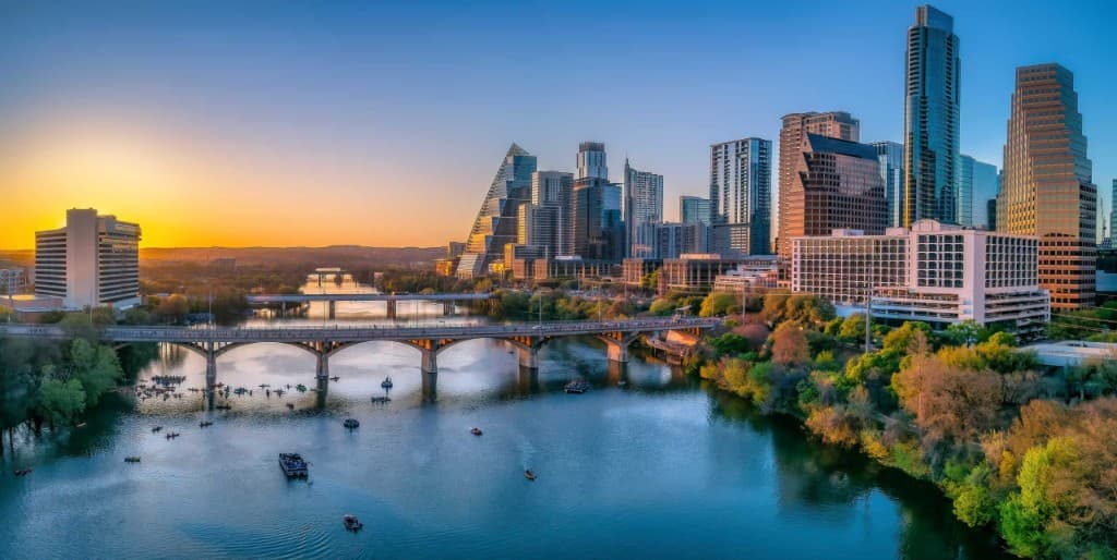 Austin skyline at sunset along Lady Bird Lake with Congress Avenue Bridge and kayakers on the water